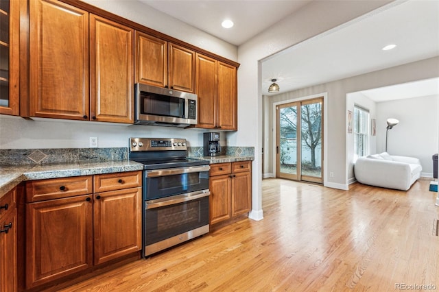 kitchen with stainless steel appliances, brown cabinets, and glass insert cabinets