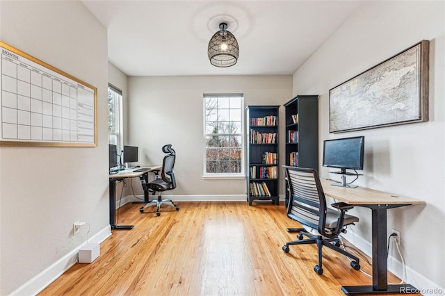 home office with light wood-style flooring and baseboards