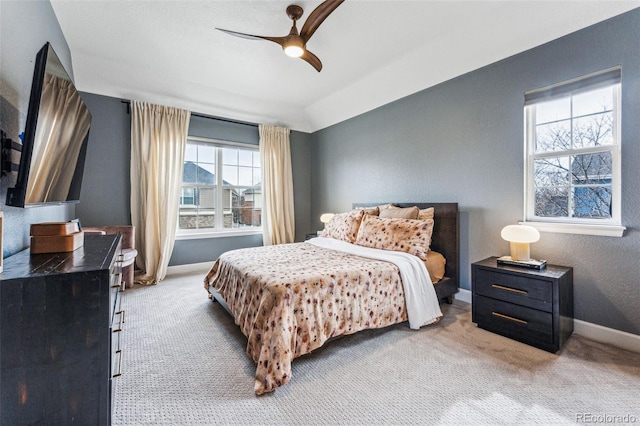 bedroom with a ceiling fan, light carpet, a textured wall, and baseboards