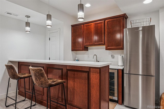 kitchen featuring freestanding refrigerator, light countertops, hanging light fixtures, and visible vents