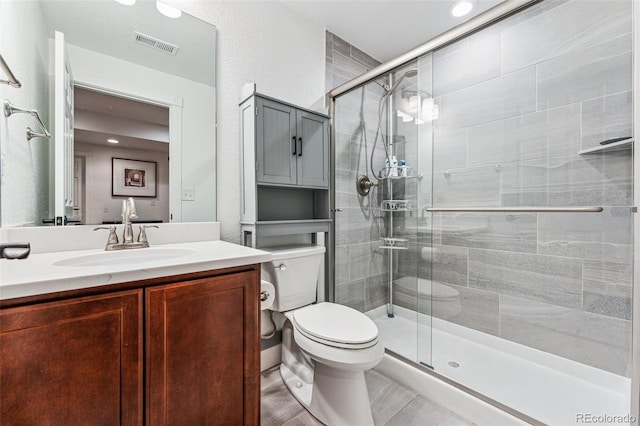 full bath featuring a textured wall, toilet, vanity, visible vents, and a stall shower