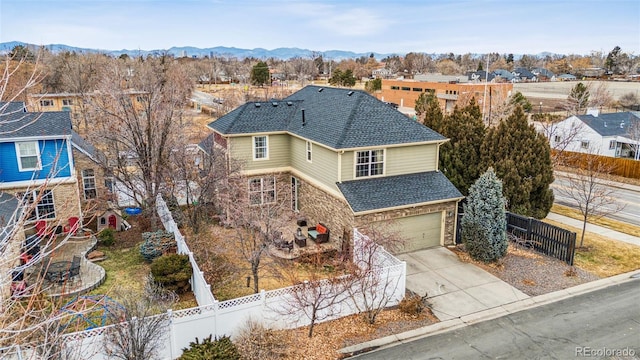 view of front of home featuring a shingled roof, concrete driveway, a mountain view, a garage, and fence private yard