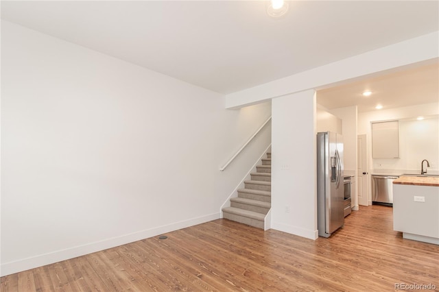 unfurnished living room featuring sink and light wood-type flooring