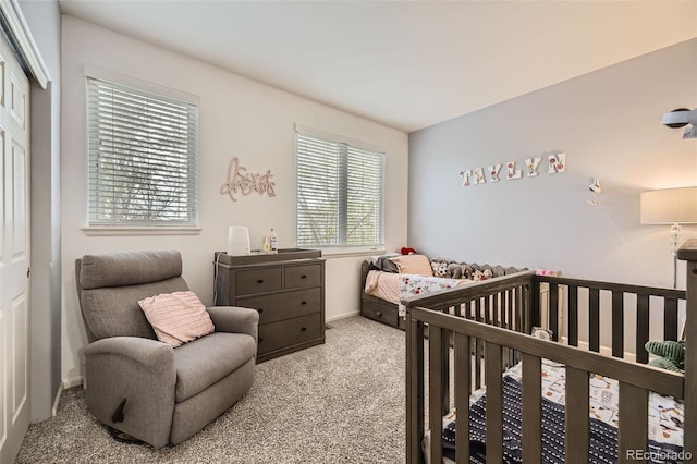 bedroom featuring baseboards, a crib, carpet, and a closet