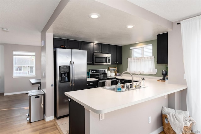 4304 S Genoa Ct, Centennial, CO 80015 - kitchen with appliances with stainless steel finishes, dark cabinets, a peninsula, light countertops, and a textured ceiling