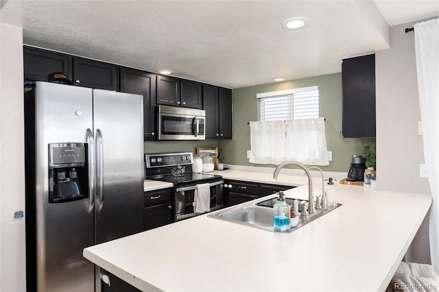 4304 S Genoa Ct, Centennial, CO 80015 - kitchen with appliances with stainless steel finishes, dark cabinetry, a peninsula, light countertops, and recessed lighting