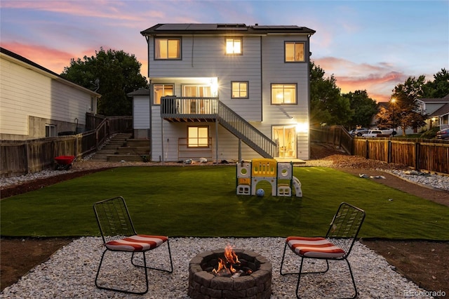 4304 S Genoa Ct, Centennial, CO 80015 - back of property at dusk featuring an outdoor fire pit, stairway, a fenced backyard, solar panels, and a wooden deck