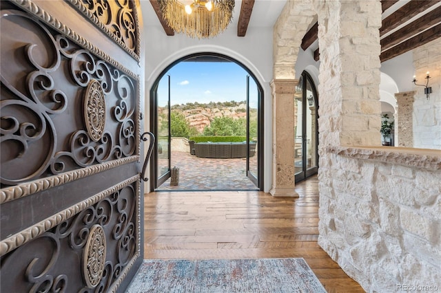 entryway featuring beamed ceiling, ornate columns, and hardwood / wood-style flooring