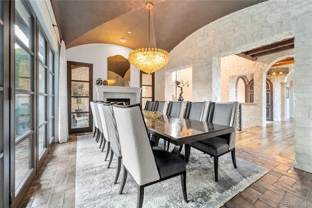 7944 Dante Dr, Littleton, CO 80125 - dining space with lofted ceiling, a notable chandelier, arched walkways, and stone tile flooring