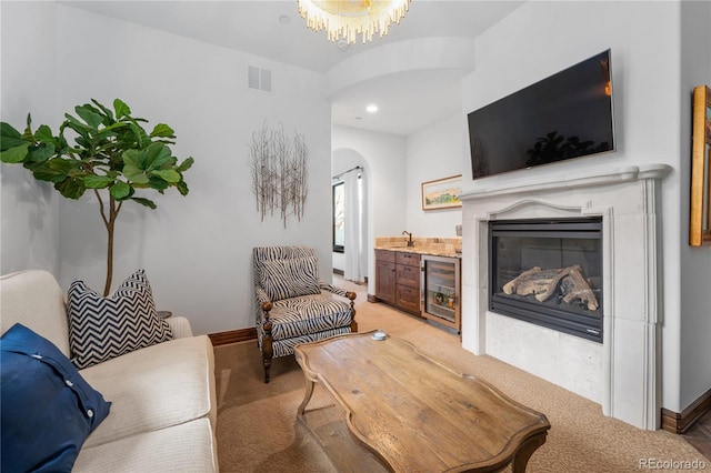 7944 Dante Dr, Littleton, CO 80125 - living room with arched walkways, beverage cooler, visible vents, light carpet, and a glass covered fireplace