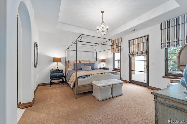 bedroom featuring light carpet, a notable chandelier, and a raised ceiling