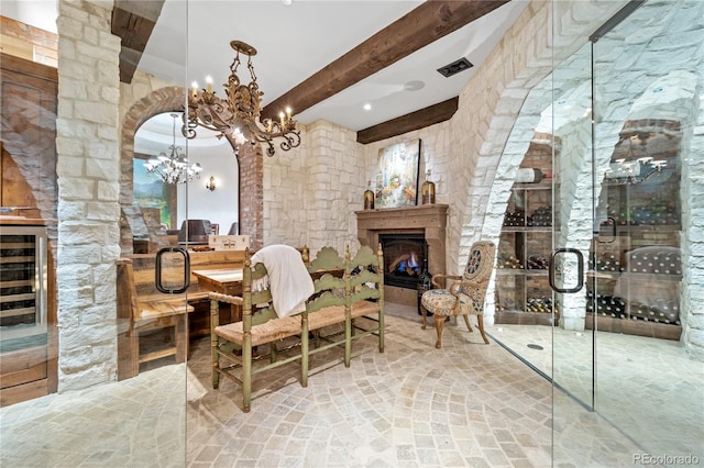 wine area featuring beamed ceiling and a chandelier