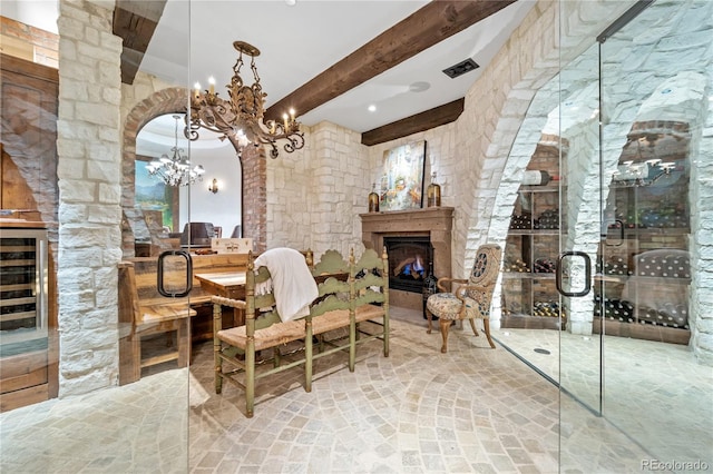 7944 Dante Dr, Littleton, CO 80125 - dining area featuring visible vents, beamed ceiling, a fireplace, beverage cooler, and a notable chandelier