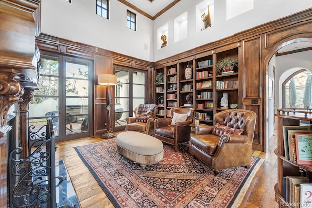 living area with ornamental molding, a high ceiling, a wealth of natural light, and hardwood / wood-style flooring