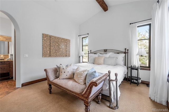 bedroom featuring lofted ceiling with beams, light carpet, and ensuite bathroom