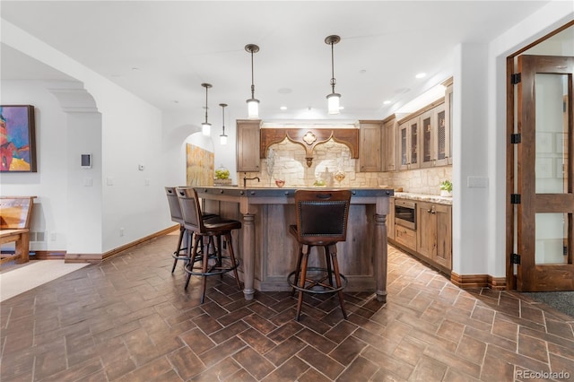 7944 Dante Dr, Littleton, CO 80125 - bar featuring decorative backsplash, baseboards, recessed lighting, arched walkways, and hanging light fixtures