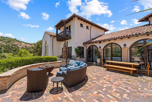 view of patio featuring a balcony and an outdoor living space with a fire pit