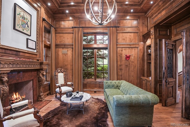 living area featuring wooden walls, ornamental molding, a chandelier, a premium fireplace, and wood finished floors