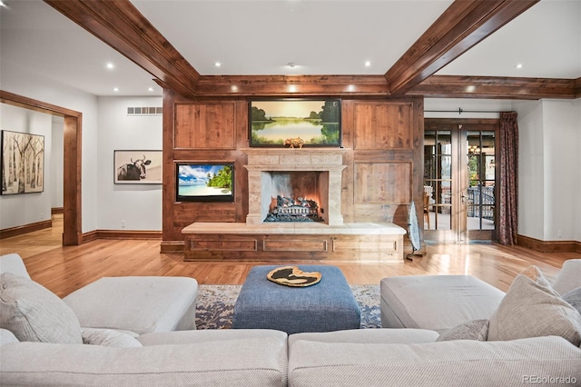 living room with light wood-type flooring, baseboards, a fireplace, and crown molding