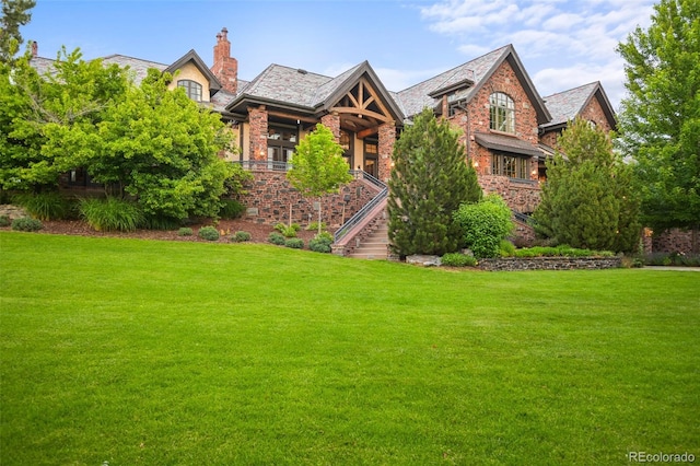 english style home with a front yard, stairs, and brick siding