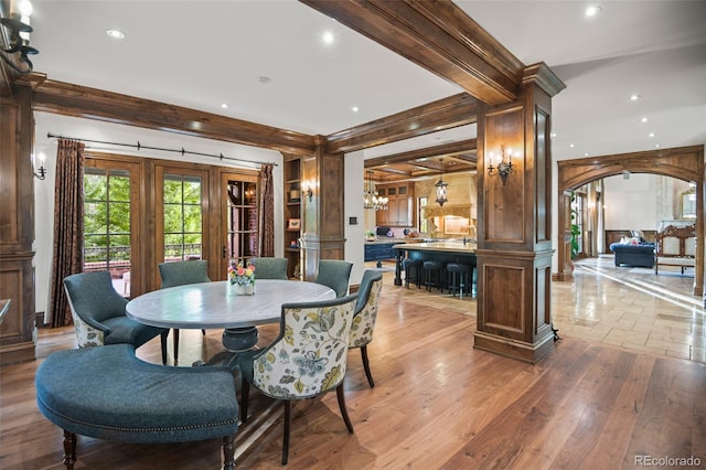 dining space featuring ornate columns, a chandelier, recessed lighting, arched walkways, and light wood-type flooring