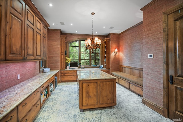 kitchen with a chandelier, a kitchen island, brown cabinets, recessed lighting, and light stone counters