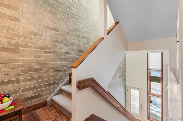 staircase with brick wall and a high ceiling