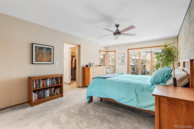 bedroom with light carpet, a walk in closet, and ceiling fan