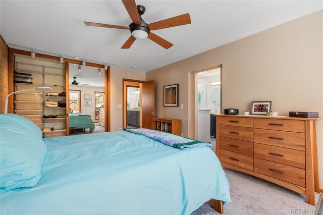 carpeted bedroom with ensuite bath and ceiling fan