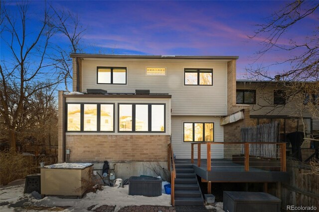 back house at dusk with a wooden deck and a sunroom