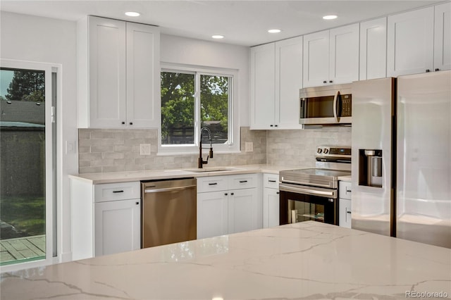 9605 Carr St, Broomfield, CO 80021 - kitchen with stainless steel appliances, a sink, light stone countertops, backsplash, and white cabinetry