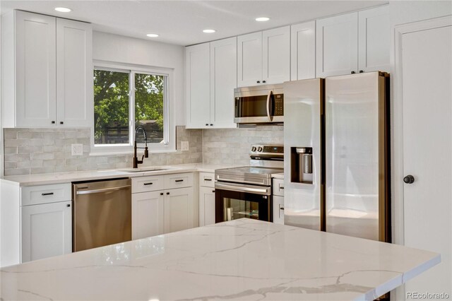 9605 Carr St, Broomfield, CO 80021 - kitchen featuring appliances with stainless steel finishes, a sink, tasteful backsplash, white cabinets, and light stone countertops