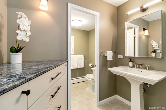 bathroom with a baseboard heating unit, tile patterned floors, sink, and toilet