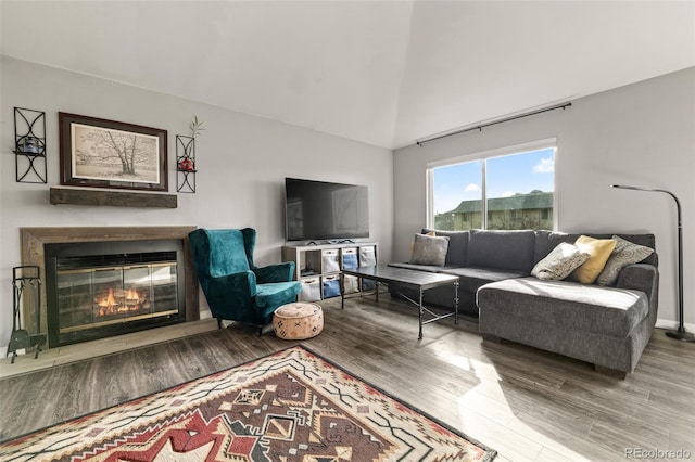 living area with a glass covered fireplace, wood finished floors, and a towering ceiling