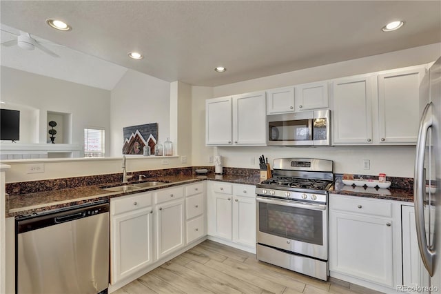 21541 Unbridled Ave, Parker, CO 80138 - kitchen with appliances with stainless steel finishes, a sink, white cabinets, lofted ceiling, and dark stone countertops
