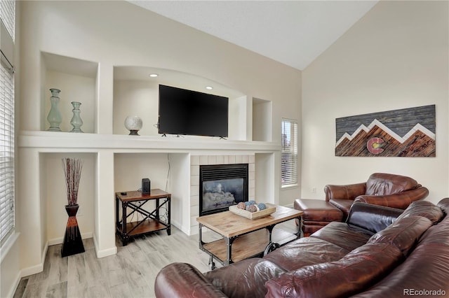 21541 Unbridled Ave, Parker, CO 80138 - living area featuring a tiled fireplace, wood finished floors, high vaulted ceiling, and baseboards