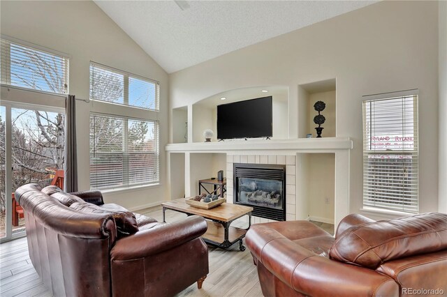 21541 Unbridled Ave, Parker, CO 80138 - living area featuring high vaulted ceiling, a tile fireplace, light wood-type flooring, and baseboards