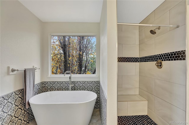 21541 Unbridled Ave, Parker, CO 80138 - bathroom featuring tile walls, a freestanding bath, tiled shower, wainscoting, and tile patterned floors