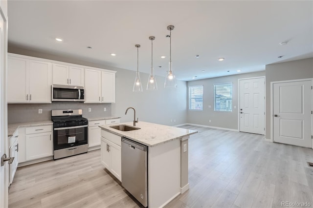 kitchen with white cabinetry, sink, hanging light fixtures, an island with sink, and appliances with stainless steel finishes