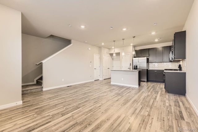 kitchen with baseboards, open floor plan, light wood-style floors, stainless steel refrigerator with ice dispenser, and tasteful backsplash