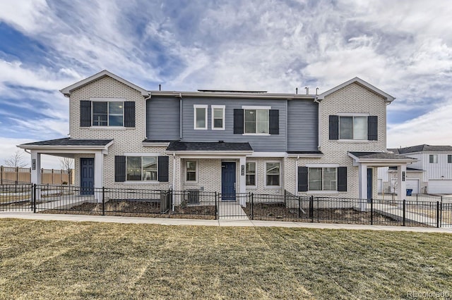 view of front of property featuring a fenced front yard, brick siding, and a front lawn