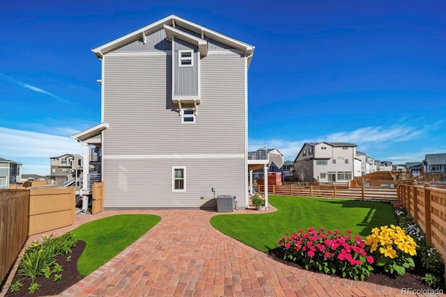 rear view of property featuring a yard, a patio, and central AC