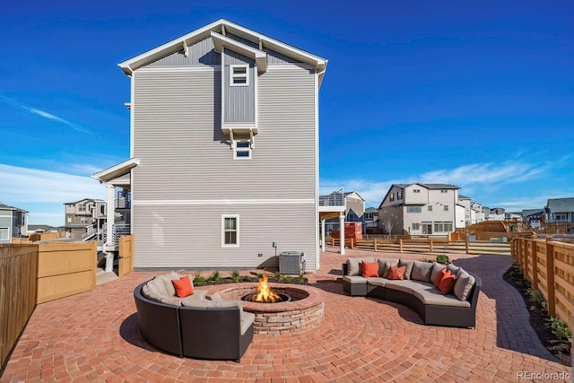 back of property featuring central AC unit, a patio, and an outdoor living space with a fire pit