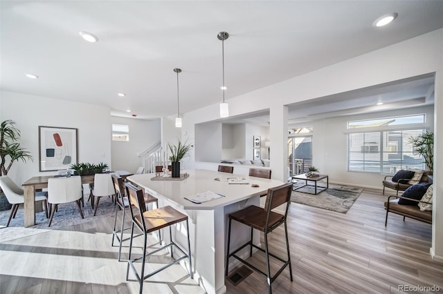 kitchen with decorative light fixtures, a kitchen breakfast bar, and light hardwood / wood-style flooring