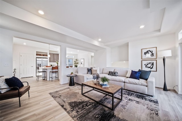 living room with light wood-type flooring and a tray ceiling