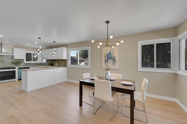 1596 S Stuart St, Denver, CO 80219 - dining space featuring light wood finished floors, a chandelier, and a textured ceiling