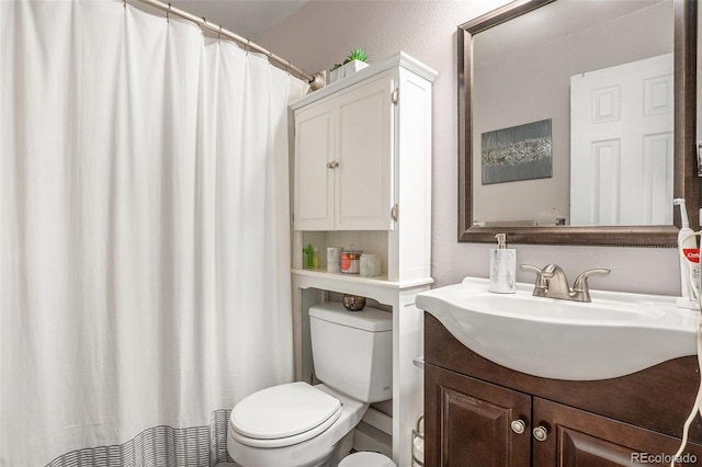 bathroom with toilet, vanity, and a textured wall