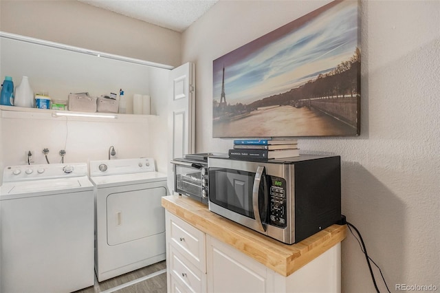 laundry area featuring laundry area, washing machine and dryer, a textured ceiling, and wood finished floors