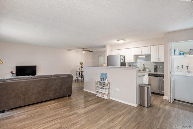 living room featuring light wood-type flooring, a textured ceiling, washer / dryer, and ceiling fan