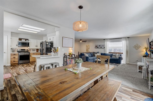 dining area with light wood finished floors, ceiling fan, and baseboards